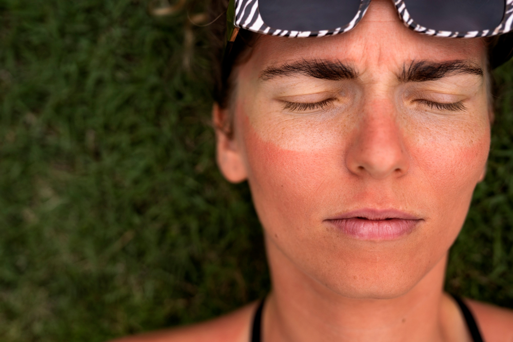 mujer con bronceado, ojos cerrados y lentes de sol sobre la frente