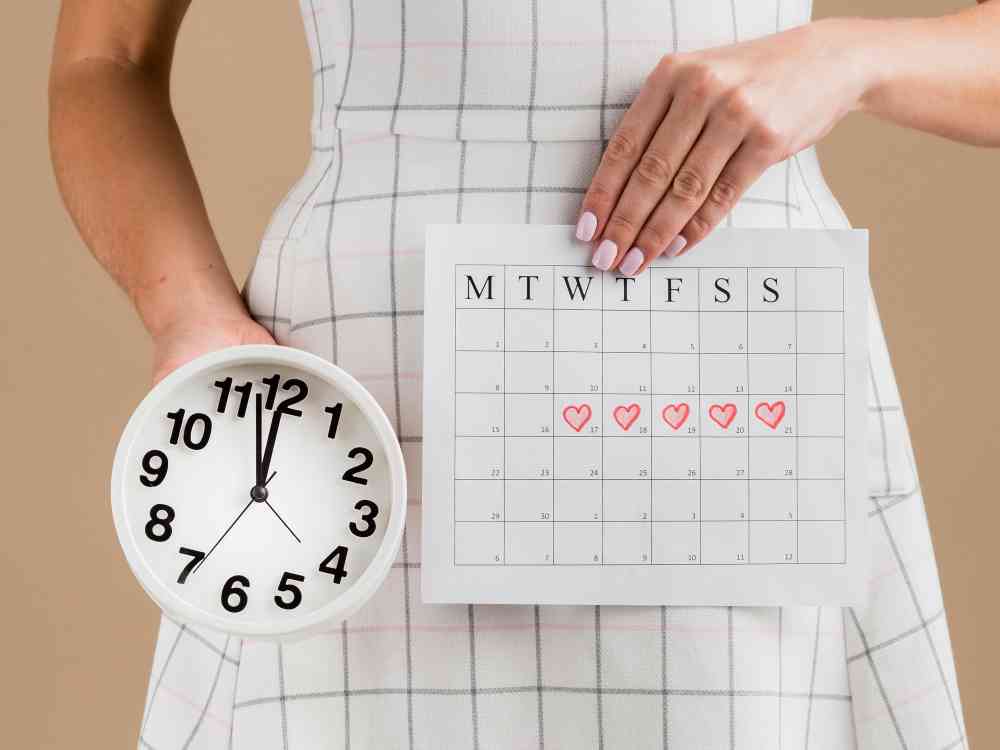 fases del ciclo menstrual - mujer sosteniendo calendario y hora